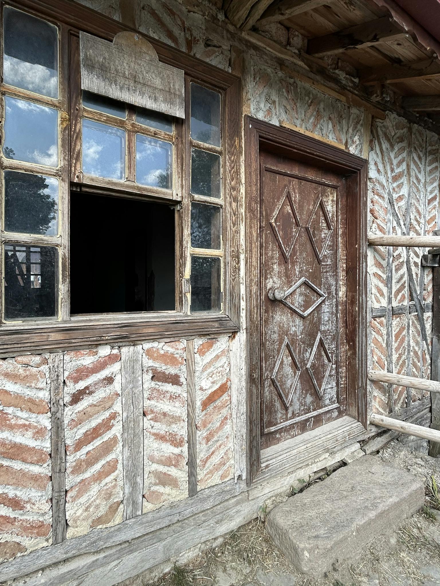 Old wooden door and window on a rustic, weathered house exterior with textured walls.