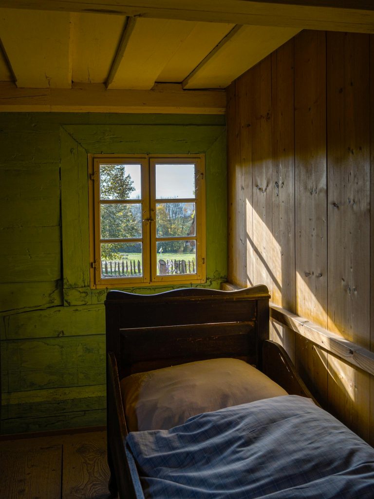 Sunlight streaming into a rustic farmhouse bedroom, highlighting serene outdoor views through the window.